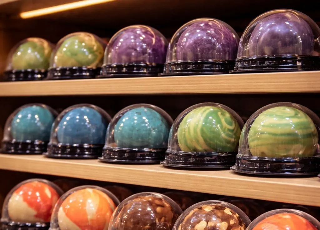 Étagères avec les bombes de chocolat chaud Chocolats artisanaux O'BomB façon planètes, gamme pour professionnels